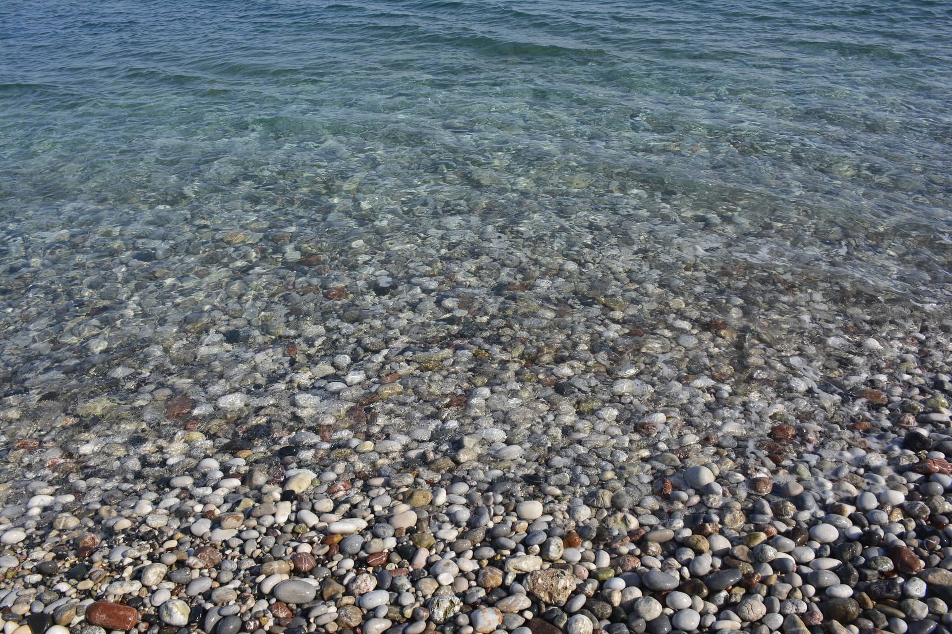 Stony beach with azure blue water and small waves at rhodes greece island – Greece, Europe. Photo: Christian Böhme