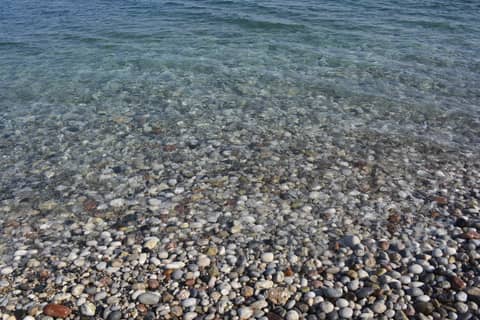 Stony beach with azure blue water and small waves at rhodes greece island